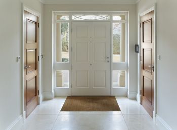 Bright entryway with white front door, sidelights, and tiled floor in a modern home